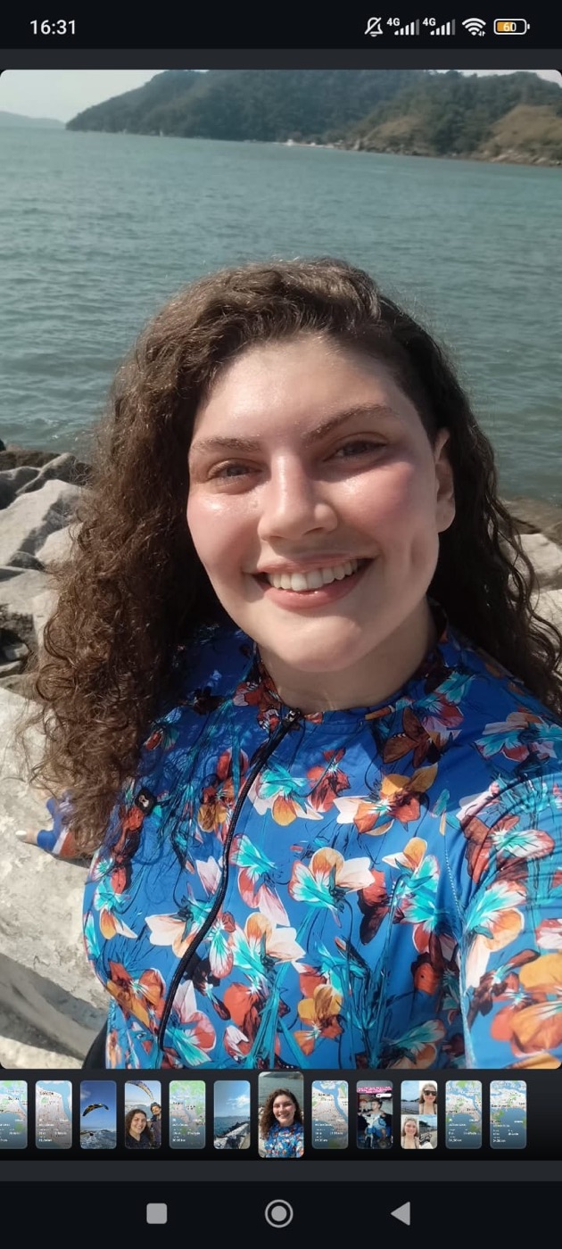 Izabeli sorrindo na praia com roupa de ciclismo